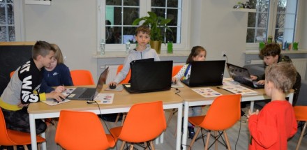 Uczestnicy warsztatów grafiki komputerowej siedzący przed laptopami w trakcie zajęć.