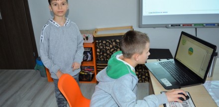 Dwóch chłopców, uczestników warsztatów grafiki komputerowej pracuje przed laptopem.