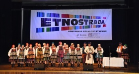 Zdjęcie grupowe jednego z zespołów ludowych, widoczni mężczyźni i kobiety ubrani w kolorowe stroje.