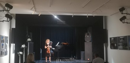 Kobieta na scenie trzyma skrzypce.