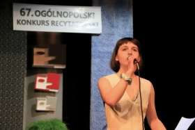 67. Ogólnopolski Konkurs Recytatorski - uczestniczka z mikrofonem stoi na scenie.
