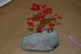 Kamień jest opleciony miedzianym drucikiem wraz z czerwonymi koralikami. Wygląda jakby drzewo wyrastało z tego kamienia.