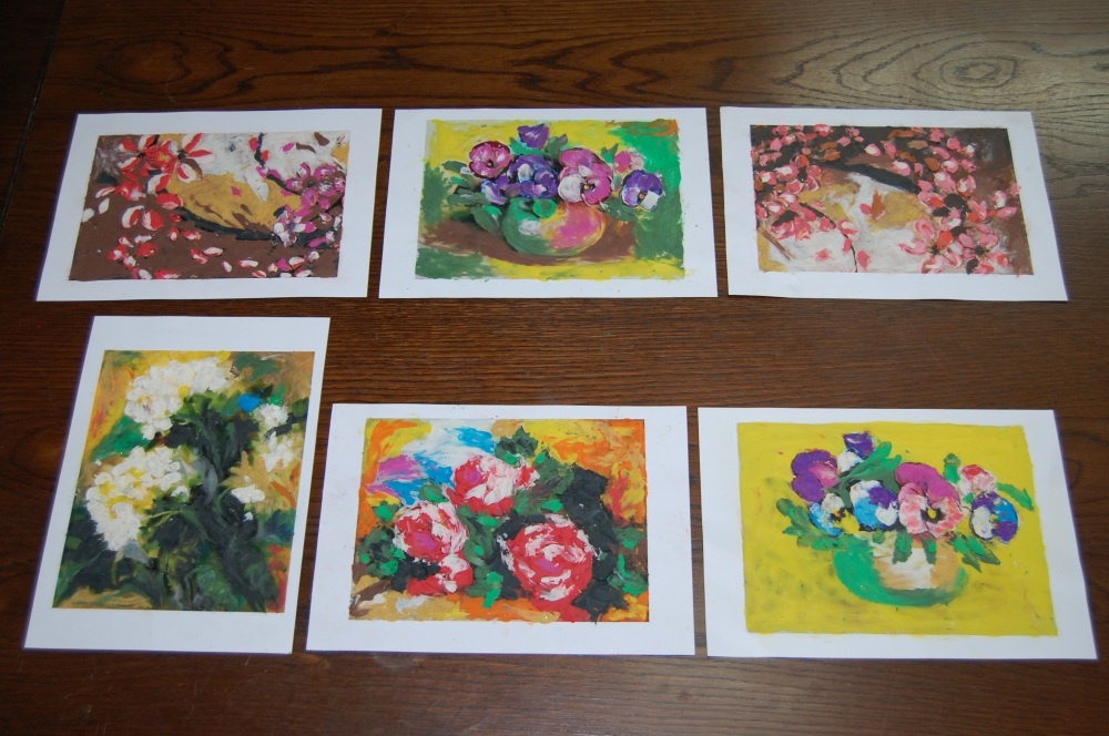 Zdjęcie prac wykonanych kredkami przez uczestników zajęć plastycznych - kolorowe kwiaty.