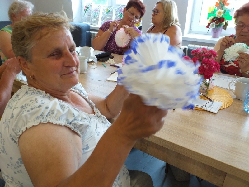 Uczestniczki warsztatów wykonują prace plastyczne - papierowe kwiaty.