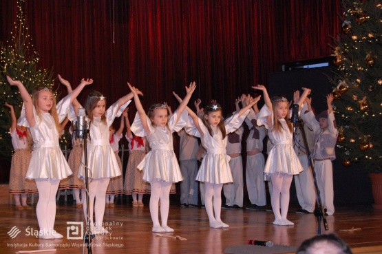 Zbliżenie na scenę - na pierwszym planie dziewczynki przebrane za aniołki, które stoją z podniesionymi rękami