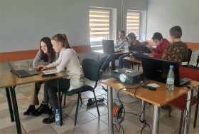Młodzież w trakcie warsztatów z grafiki komputerowej pracuje na laptopach. Widoczny projektor.