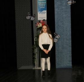 Młoda uczestniczka konkursu, stojąca na scenie w trakcie występu. 