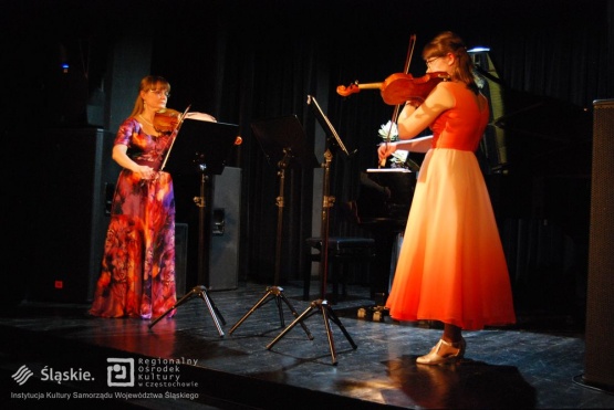 Dwie artystki grają na skrzypcach - zbliżenie.