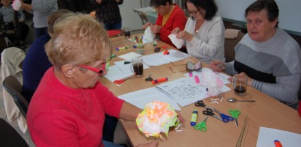 Uczestniczka warsztatów wykonująca papierowy kwiat koloru biało-pomarańczowego.