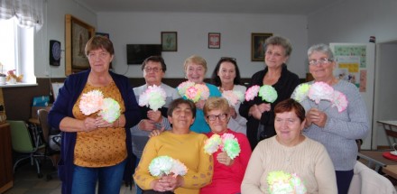 Zdjęcie grupowe uczestniczek zajęć plastycznych - prezentacja wykonanych kwiatów z papieru. 