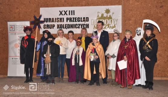 Zdjęcie grupowe - organizatorzy i jedna z grup biorących udział w konkursie stoi na scenie. Widoczne kostiumy króli, kostuchy, diabła, policjanta.