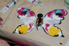 Pomalowany drewniany motyl w kolorach biało-czerwono-czarno-żółto-niebieskich - oddalone zdjęcie.