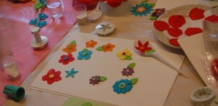 Praca wykonana przez uczestnika warsztatów - kwiaty z plasteliny przyklejone na kartce.