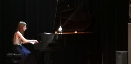 Kobieta gra na fortepianie na scenie.