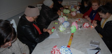 Uczestnicy zajęć plastycznych w trakcie wykonywania prac - papierowych kwiatów.