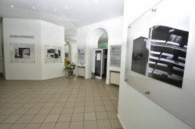Biały korytarz pokryty lustrami i innymi obrazami. Jest to wnętrze galerii fotobudkowej.