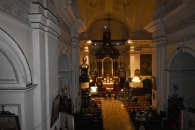 Zdjęcie wykonane z perspektywy chóru kościelnego. Widać zakończenia ścian oraz sufit. W tle znajduje się ołtarz.