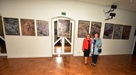 Dwie kobiety stojące przy drzwiach. Za nimi wiszą na ścianach obrazy.