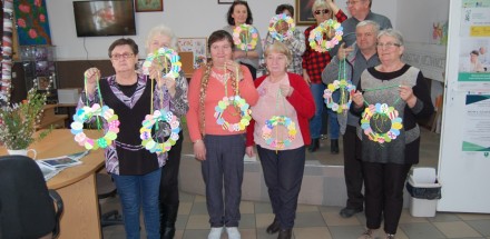 Zdjęcie grupowe uczestników warsztatów plastycznych, którzy prezentują wykonane prace - kolorowe jajka wielkanocne.