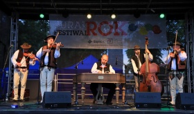 Zespół muzyków składających się z trzech mężczyzn. Po lewej stronie mężczyzna gra na skrzypcach, w środku na organach, po prawej stronie na kontrabasie