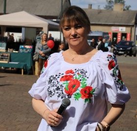 Kobieta w koszulce ze wzorami folklorystycznymi z mikrofonem w ręce