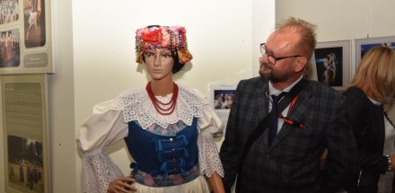 Uczestnik wernisażu przygląda się manekinowi ubranemu w Śląski strój ludowy.